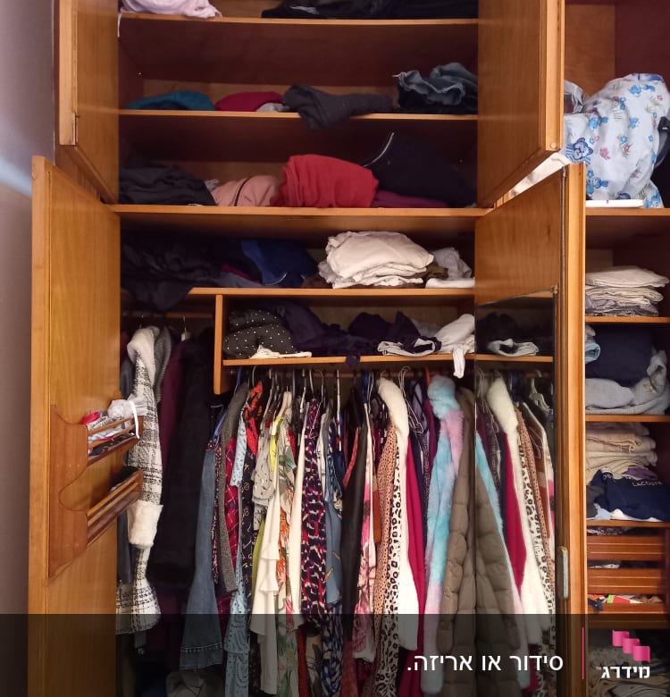 ארון בגדים עם מדפים מלאים בבגדים מקופלים ותלויים